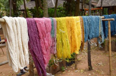 Ahşap kazıkta renkli ham iplik.