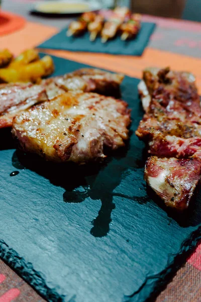 Taze pişmiş domuz eti ve yanında siyah bir tabakta patates kızartması.