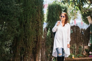 Güzel kadın gülümseyen kot pantolon, beyaz gömlek ve koyu güneş gözlüğü. Yaşam tarzı. sokak kentsel tarzı.