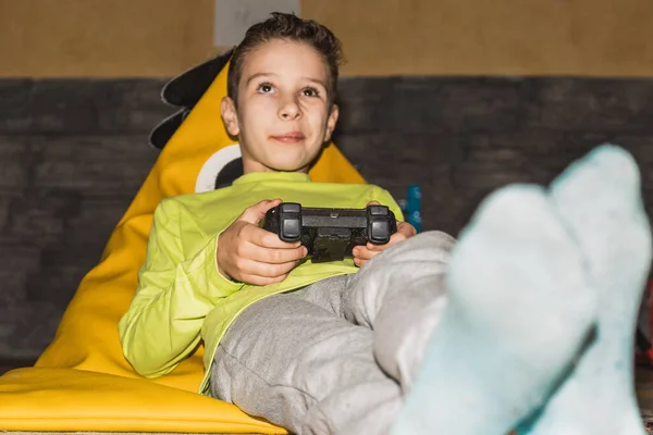 Bambino Che Gioca Videogiochi Sdraiato Pouf Indossando Una Maglietta Gialla — Foto Stock