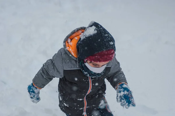 Мальчик Ходит Колено Снегу Разноцветной Зимней Одежде Маске Ковидного Цвета Стоковое Фото