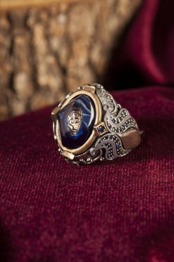 Bordo kadife arka planda erkek gümüş yüzüğü tasarla.