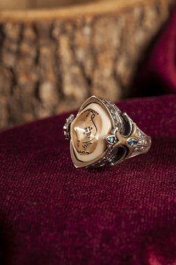 Bordo kadife arka planda erkek gümüş yüzüğü tasarla.