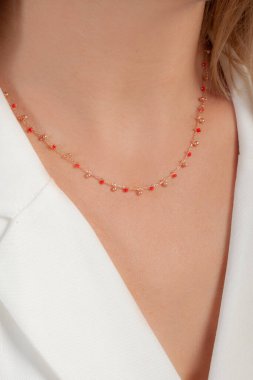 Zarif ve bakımlı, sarı saçlı, beyaz saçlı bir kadının boynuna takılmış renkli bir kolye.