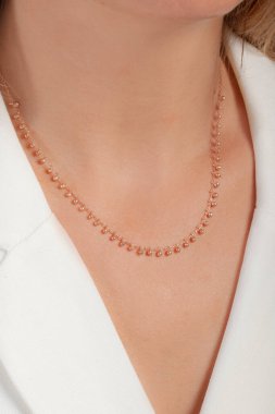 Zarif ve bakımlı, sarı saçlı, beyaz saçlı bir kadının boynuna takılmış renkli bir kolye.