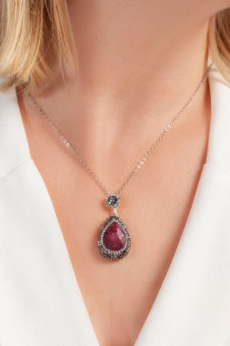 Sarışın kadının üzerinde beyaz bir elbise olan gösterişli bir kolye.