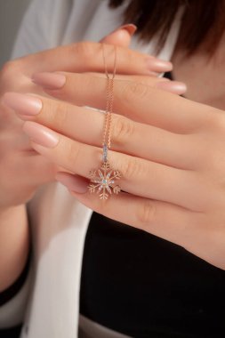 Çok güzel kolyeler ve bakımlı tırnaklar sunar. Parlak kolyesi olan güzel genç bir kadın..