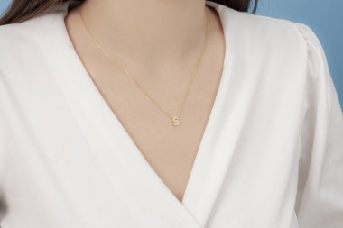 Altın ve gümüş kolye bakımlı, zarif, beyaz giysili bayana