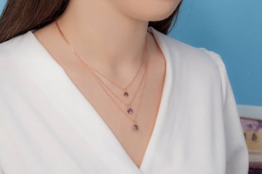 Altın ve gümüş kolye bakımlı, zarif, beyaz giysili bayana