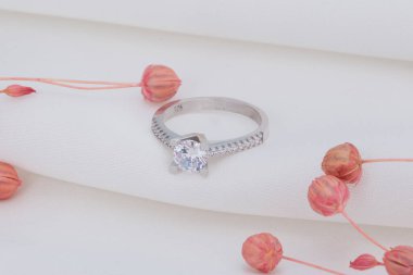 Katmanlı beyaz arka planda pembe çiçekler ve gümüş yüzük