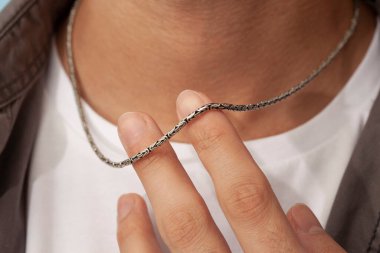 Gri tişört ve beyaz tişört giyen adamın boynunda gümüş bir kolye var. e-ticaret erkeklerin ürün satış imajı. 