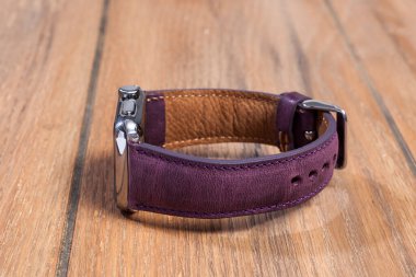 Ahşap zemindeki akıllı saate bağlı mor deri kayış..