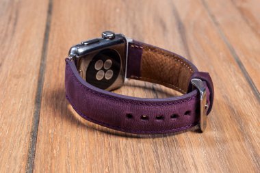 Ahşap zemindeki akıllı saate bağlı mor deri kayış..
