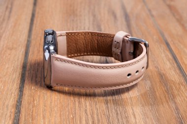 Ahşap zemindeki akıllı saate bağlı pembe deri kayış..