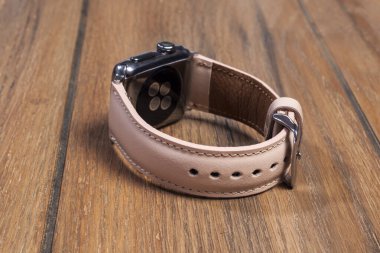 Ahşap zemindeki akıllı saate bağlı pembe deri kayış..