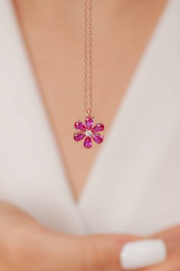 Çok güzel kolyeler ve bakımlı tırnaklar sunar. Parlak kolyesi olan güzel genç bir kadın..