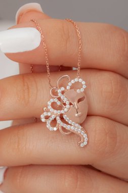 Çok güzel kolyeler ve bakımlı tırnaklar sunar. Parlak kolyesi olan güzel genç bir kadın..