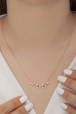 Tırnakları bakımlı olan bayan, çok güzel kolyeler veriyor. Gümüş, elmas, altın kolyeler.