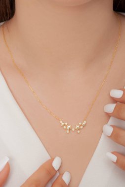 Tırnakları bakımlı olan bayan, çok güzel kolyeler veriyor. Gümüş, elmas, altın kolyeler.