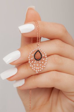 Çok güzel kolyeler ve bakımlı tırnaklar sunar. Parlak kolyesi olan güzel genç bir kadın..