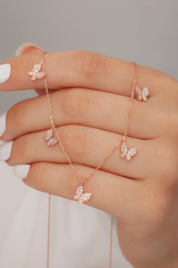 Çok güzel kolyeler ve bakımlı tırnaklar sunar. Parlak kolyesi olan güzel genç bir kadın..