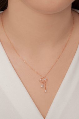 Çok güzel kolyeler ve bakımlı tırnaklar sunar. Parlak kolyesi olan güzel genç bir kadın..