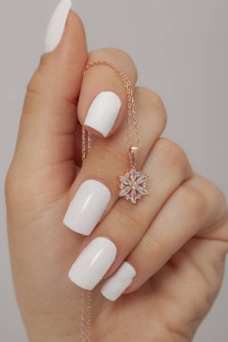 Çok güzel kolyeler ve bakımlı tırnaklar sunar. Parlak kolyesi olan güzel genç bir kadın..