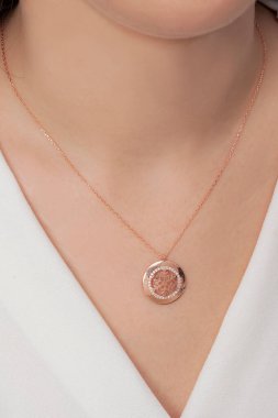 Beyazlar içindeki kızın boynunda zarif bir kolye var.