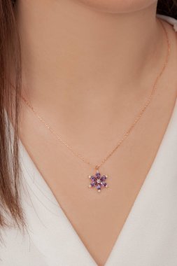 Beyazlar içindeki kızın boynunda zarif bir kolye var.