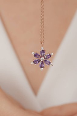 Çok güzel kolyeler ve bakımlı tırnaklar sunar. Parlak kolyesi olan güzel genç bir kadın..