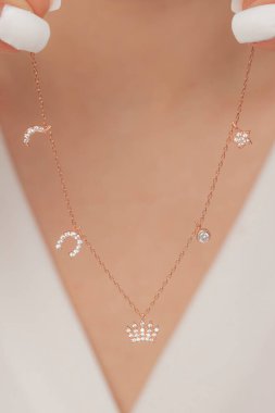 Çok güzel kolyeler ve bakımlı tırnaklar sunar. Parlak kolyesi olan güzel genç bir kadın..