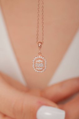 Çok güzel kolyeler ve bakımlı tırnaklar sunar. Parlak kolyesi olan güzel genç bir kadın..