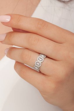 Kadın parmağında zarif gümüş bir yüzük. Çevrimiçi satış için yüzük, bakımlı ellerde parlıyor.