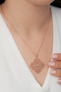 Çok güzel kolyeler ve bakımlı tırnaklar sunar. Parlak kolyesi olan güzel genç bir kadın..