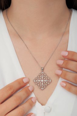 Çok güzel kolyeler ve bakımlı tırnaklar sunar. Parlak kolyesi olan güzel genç bir kadın..