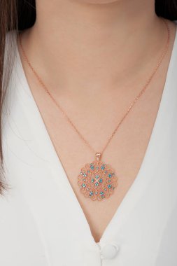 Çok güzel kolyeler ve bakımlı tırnaklar sunar. Parlak kolyesi olan güzel genç bir kadın..