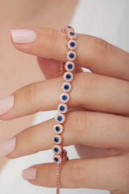 Tırnakları bakımlı bayan güzel bilezikler sergiliyor..