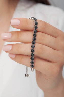 Tırnakları bakımlı bayan güzel bilezikler sergiliyor..