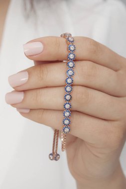 Tırnakları bakımlı bayan güzel bilezikler sergiliyor..