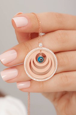 Çok güzel kolyeler ve bakımlı tırnaklar sunar. Parlak kolyesi olan güzel genç bir kadın..