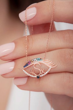 Çok güzel kolyeler ve bakımlı tırnaklar sunar. Parlak kolyesi olan güzel genç bir kadın..