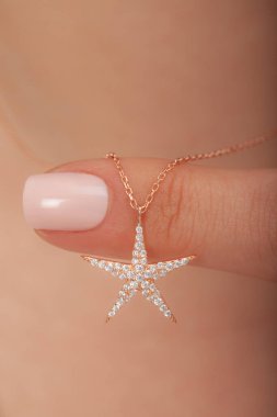 Çok güzel kolyeler ve bakımlı tırnaklar sunar. Parlak kolyesi olan güzel genç bir kadın..