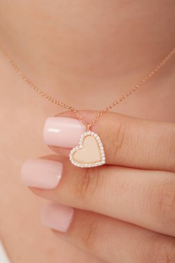 Çok güzel kolyeler ve bakımlı tırnaklar sunar. Parlak kolyesi olan güzel genç bir kadın..