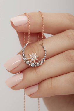 Çok güzel kolyeler ve bakımlı tırnaklar sunar. Parlak kolyesi olan güzel genç bir kadın..