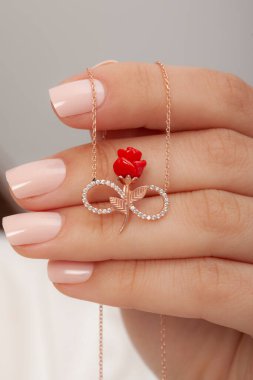 Çok güzel kolyeler ve bakımlı tırnaklar sunar. Parlak kolyesi olan güzel genç bir kadın..