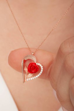 Çok güzel kolyeler ve bakımlı tırnaklar sunar. Parlak kolyesi olan güzel genç bir kadın..