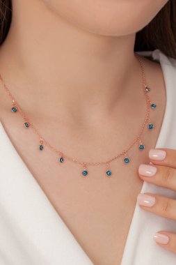 Tırnakları bakımlı olan bayan, çok güzel kolyeler veriyor. Gümüş, elmas, altın kolyeler.