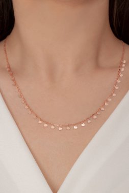 Tırnakları bakımlı olan bayan, çok güzel kolyeler veriyor. Gümüş, elmas, altın kolyeler.