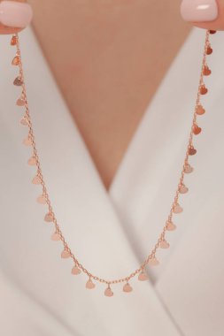 Çok güzel kolyeler ve bakımlı tırnaklar sunar. Parlak kolyesi olan güzel genç bir kadın..