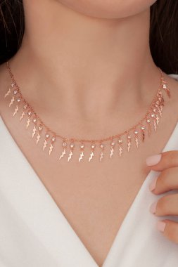 Tırnakları bakımlı olan bayan, çok güzel kolyeler veriyor. Gümüş, elmas, altın kolyeler.